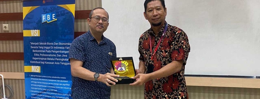 Dekan FEB Universitas Mulia Dr. Ivan Armawan menyerahkan cenderamata kepada Wakil Dekan FBE Ubaya Fidelis Arastyo Andono, S.E., M.M., Ph.D., Ak. Foto: dok. FEB